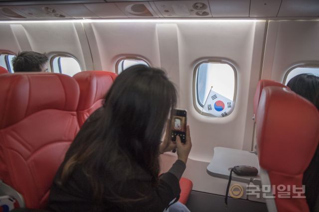 비행기 창에 태극기를 놓고 스마트폰으로 찍고 있는 탑승객.