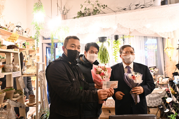 소강석(오른쪽) 목사가 경기 용인시 보정동 카페거리 수에뜨리꽃집을 찾아 운제후(왼쪽) 대표에게 상품권을 건네고 상품을 구입했다. 가운데는 백군기 용인시장. 새에덴교회 제공