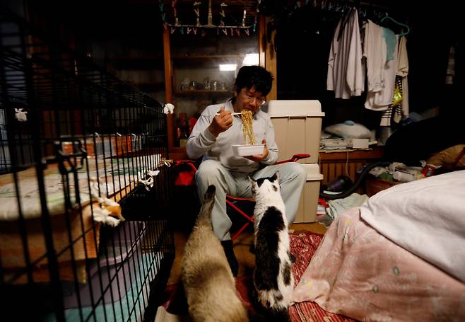 2021년 2월20일 후쿠시마원전 인근 제한지역에서 41마리의 고양이를 키우고 있는 사케 카토씨가 라면을 먹고 있다./ REUTERS