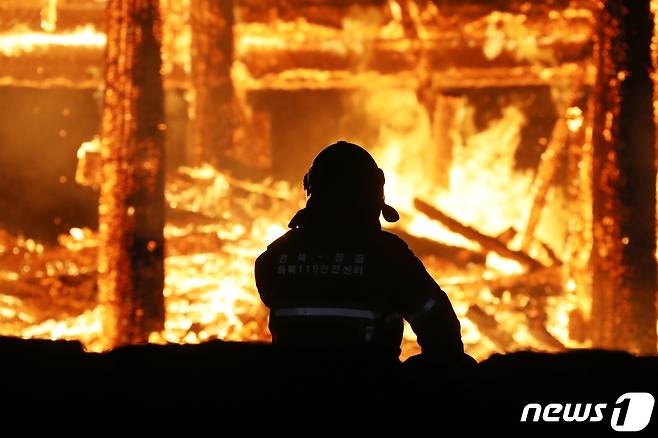 5일 오후 6시 50분께 전북 정읍시 내장사 대웅전에서 방화로 추정되는 화재가 발생해 불길이 치솟고 있다. 한 소방관이 불길을 잡기 위해 안간힘을 쓰고 있다.(정읍시 제공) 2021.3.5/뉴스1 © News1 박제철 기자
