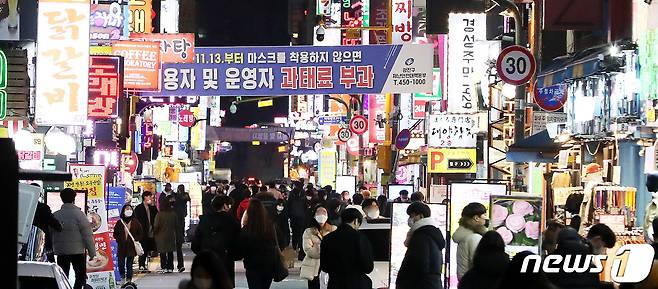 정부의 사회적 거리두기 2단계 시행을 하루 앞둔 23일 서울 광진구 건대맛의거리 화려한 네온사인 사이로 시민들이 지나가고 있다. 2020.11.23/뉴스1 © News1 박지혜 기자