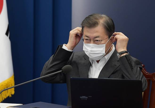 Struggling: President Moon Jae-in puts on his mask after making a comment during a meeting with his senior secretaries and aides at Cheongwadae on March 15. Cheongwadae press photographers