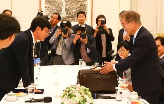 지난 2017년 야당 반대로 청문회 보고서 채택없이 임명된 김상조 공정위원장(왼쪽)의 임명식 당시 청와대는 낡은 가방을 부각시켰다. 문재인 대통령은 ″물욕 없는 굵곡진 삶″이라고 했지만 최근 드러난 삶은 이와 전혀 달랐다. [중앙포토]