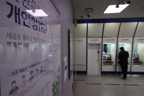 4일 서울 시내 한 시중은행에 개인형 퇴직연금(IRP) 안내문이 붙어 있는 가운데 한 고객이 현금자동입출금기(ATM)를 이용하고 있다. [한주형 기자]