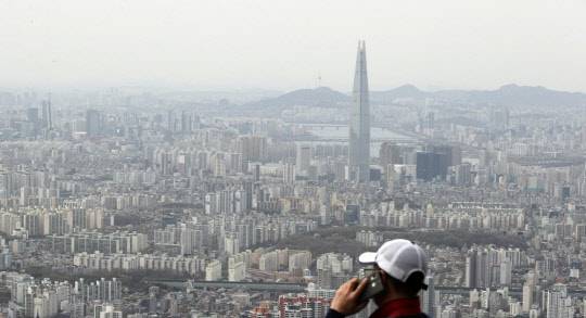 한 시민이 송파구, 강남구 일대 아파트 밀집 지역을 바라보며 전화통화하고 있다. <연합뉴스>