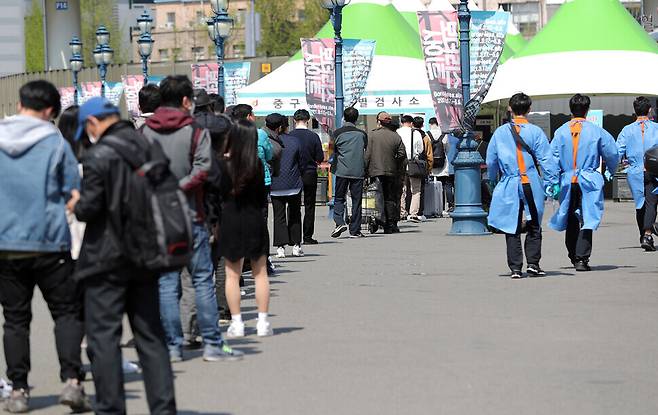 People wait in line for COVID-19 testing Wednesday at a temporary screening center set up on the plaza in front of Seoul Station. (Lee Jong-keun/The Hankyoreh)