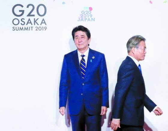 문재인 대통령이 2019년 오사카에서 열린 G20 정상회의 공식환영식에서 의장국인 일본 아베 신조 총리와 악수한 뒤 이동하고 있다. 연합뉴스