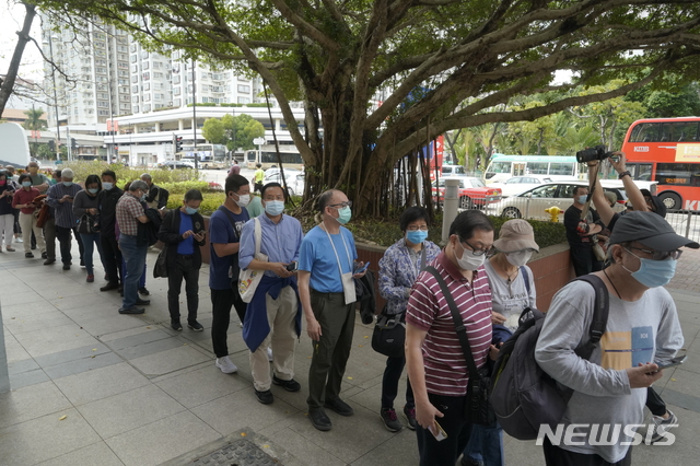 [홍콩=AP/뉴시스]2월 26일 홍콩 중심가의 코로나19 백신 접종소 앞에 주민들이 줄 서 있다. 2021.2.26.