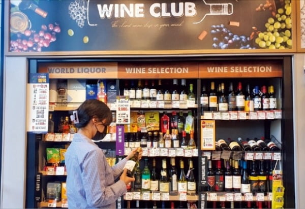 ‘홈술’ 열풍으로 집 근처 ‘슬세권’에 와인 로드숍이 늘어나고 있다. 한 소비자가 편의점 이마트24 와인 전문 코너에서 와인을 고르고 있다.  이마트24 제공