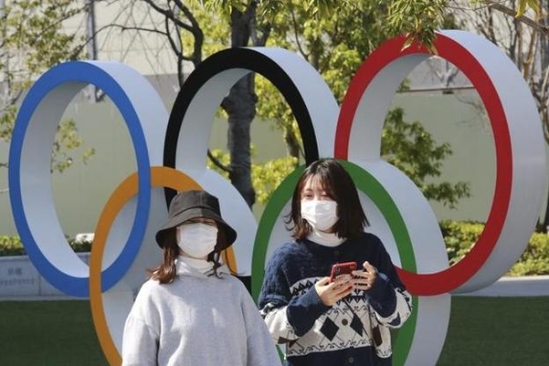 지난 3월 일본 도쿄에서 마스크를 쓴 행인들이 오륜 조형물 앞을 지나가고 있다. /연합뉴스