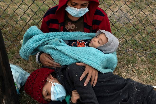 온드라스 출신 여성이 지난 8일 미국 국경에서 9개월 된 아이와 10살 아이를 안고 이민자 등록절차가 진행되는 것을 기다리고 있다. 텍사스|로이터연합뉴스