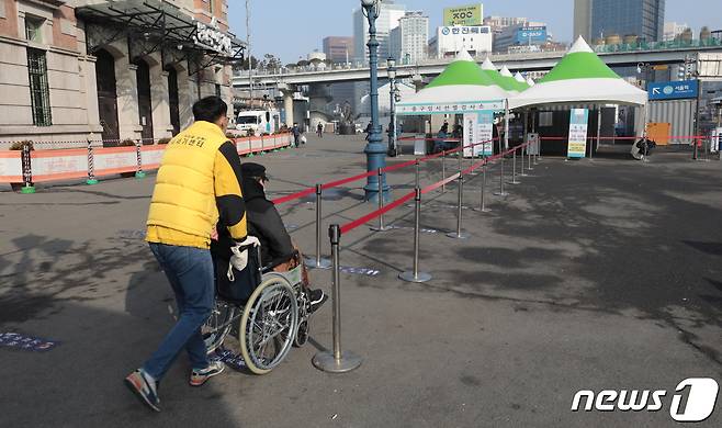 지난 2월 오전 서울역 광장에 마련된 임시 선별진료소에서 한 노숙인이 보호자와 함께 검사실로 향하고 있다. 2021.2.12/뉴스1 © News1 이성철 기자