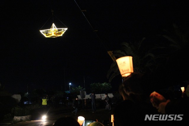 [제주=뉴시스] 제주항연안여객터미널 안에서 추모행사를 진행한 세월호촛불연대가 시민들이 직접 접은 종이배가 담은 배를 공중으로 들어 올리는 퍼포먼스를 하고 있다. (사진=뉴시스DB) photo@newsis.com