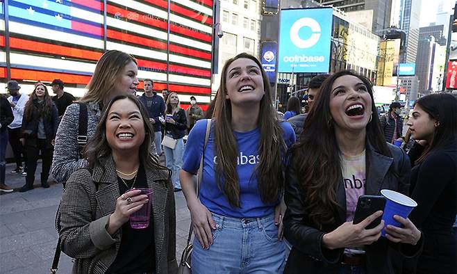 미국 최대 가상화폐거래소인 코인베이스 직원들이 14일(현지시간) 뉴욕 타임스스퀘어의 나스닥 마켓사이트 앞에서 자사의 나스닥 상장에 환호하고 있다. 뉴욕=AP연합뉴스