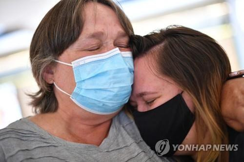 19일 호주 시드니 공항에서 뉴질랜드에서 온 딸을 껴안은 여성.[AFP=연합뉴스]