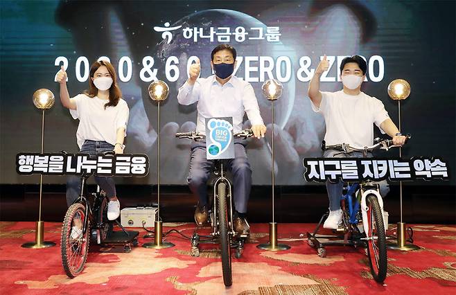 김정태 하나금융그룹 회장(사진 가운데)과 하나 핫튜버들이 22일 지구의 날을 맞아 서울 에이치펄스에서 개최한 그룹 2030 & 60 ZERO & ZERO 선언 행사에서 친환경 자가발전 자전거 세리머니를 하고 있다. (사진=하나금융)