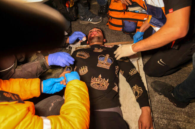 22일(현지시간) 한 팔레스타인 청년이 시위 도중 부상을 입고 들 것에 실리고 있다.  |AFP연합뉴스