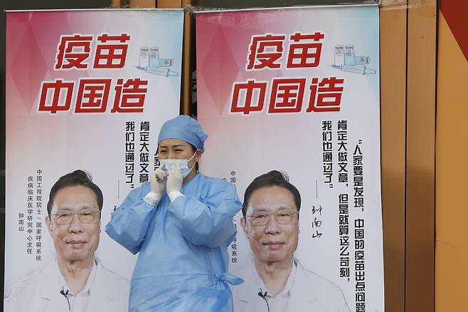 베이징의 한 중국 백신접종센터 요원이 4월9일 중국산 백신을 홍보하는 선전판 앞에 서 있다. 선전판 안의 인물은 '사스 퇴치의 영웅'으로 통하는 중난산 중국 공정원 원사이다. /AP연합