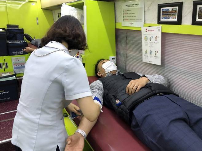 지난 20일 서울 SB타워 앞에 배치된 헌혈버스에서 골든블루 직원이 헌혈을 하고 있다.