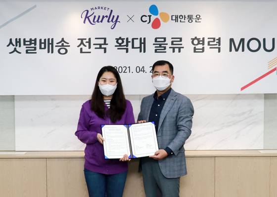 Kurly CEO Sophie Kim, left, and Kang Sin-ho, CEO at CJ Logistics, sign to cooperate on delivery of Market Kurly’s fresh produces at CJ Logistics headquarters in central Seoul on Tuesday. [CJ LOGISTICS]