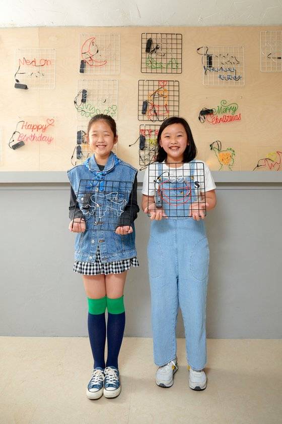 김민아(왼쪽) 학생기자·김려원 학생모델이 직접 만든 네온사인을 들고 환하게 웃었다.