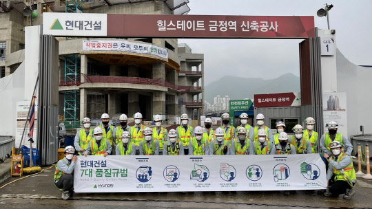 현대건설 건설현장 직원들이 2021 상반기 퀄리티 워크 포스터를 들고 기념 사진을 찍고 있다. <현대건설 제공>