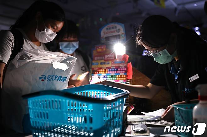 13일 대만 타이베이의 한 상점에서 손님들이 정전 사태로 인해 전구 불빛에 의존해 물건을 계산하고 있다. © 로이터=뉴스1