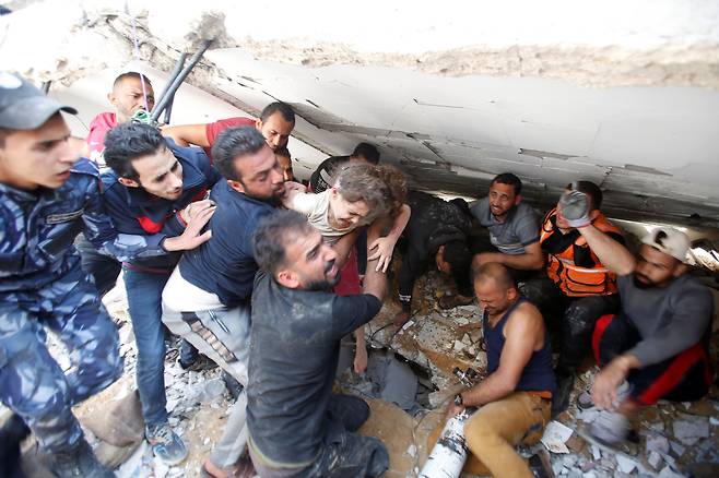 지난 16일 이스라엘 전투기 폭격으로 붕괴된 팔레스타인 가자지구 리말의 한 건물 잔해 속에서 구조대원들이 6세 소녀 수지양을 구출하고 있다. 이 건물이 붕괴한 지 7시간 만이다. 외신에 따르면 수지양은 병원에서 아버지를 만났지만, 어머니와 형제₩자매 4명은 폭격 당시 사망했다. /로이터 연합뉴스