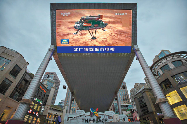 15일 중국 베이징의 한 쇼핑몰 전광판에 중국 화성 탐사선 ‘톈원 1호’ 와 로버 ‘주룽’의 화성 착륙 성공 소식이 나오고 있다. 베이징=AP 뉴시스