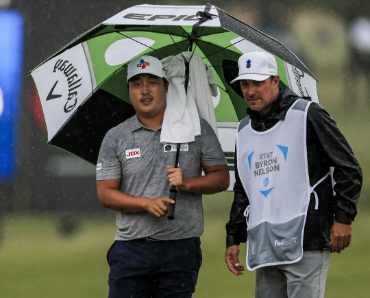이경훈(사진 왼쪽)이 17일 오전(한국시간) 열린 PGA투어 AT&T 바이런넬슨 4라운드 도중 비가 퍼붓자 캐디와 함께 우산을 쓰고 비를 피하고 있다.   EPA 연합뉴스