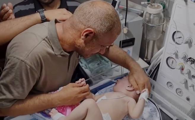 이스라엘군의 폭격으로 아내와 자녀 4명을 잃고, 유일하게 살아남은 막내 아이를 보며 눈물짓는 팔레스타인 남성