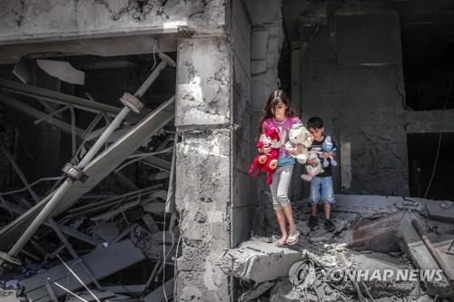 이스라엘군의 폭격으로 무너진 집에서 인형을 안고 나오는 가자지구 아이들 [AFP=연합뉴스]