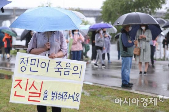 지난 16일 서울 반포한강공원 수상택시 승강장 인근에서 열린 '고 손정민 군을 위한 평화집회'에서 참가자들이 우산을 쓴 채 사건의 진상규명을 촉구하고 있다.