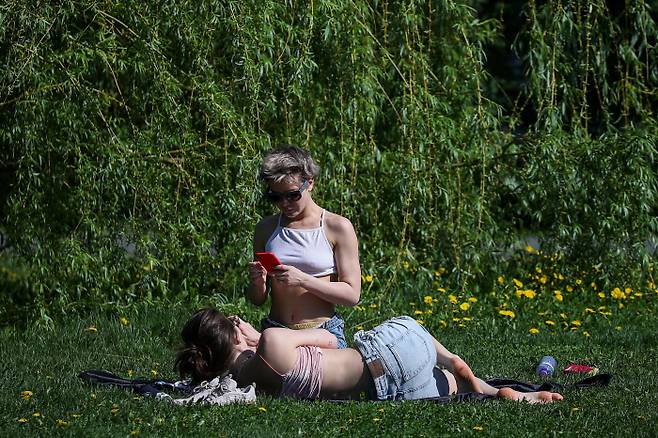 이상고온 현상이 나타난 러시아 모스크바에서 17일(현지시간) 시민들이 잔디밭에서 일광욕을 즐기고 있다. |타스연합통신