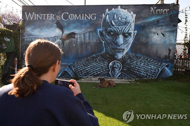 미국 캘리포니아주에 있는 HBO '왕좌의 게임' 벽화 앞에서 사진 찍는 한 주민 [AFP=연합뉴스 자료사진]