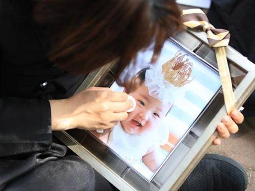 생후 16개월 된 입양아 정인이를 학대 끝에 숨지게 한 혐의를 받는 양부모의 1심 선고공판이 열린 14일 오후 서울 양천구 서울남부지법 앞에서 상복을 입은 한 시민이 정인이 사진을 닦고 있다. 뉴스1