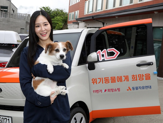 A model holds a dog in front of a Kia Ray, donated by 11st to the Korean Animal Welfare Association. 11st announced on Monday that the car was donated using the proceeds from a charity event sponsored by the e-commerce platform. The car will be used to transport animals from shelters to their families. [YONHAP]