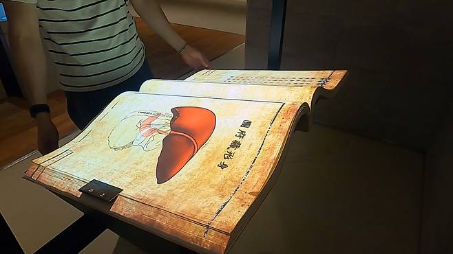 A visitor looks at a digital book that presents Heo Jun’s “Dongui Bogam,” from the Joseon Dynasty. (Kim Hae-yeon/ The Korea Herald)