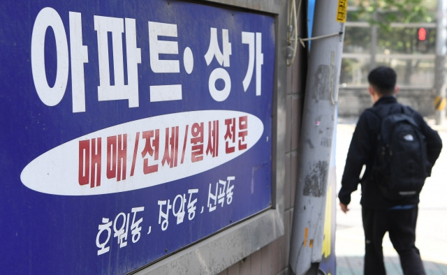 지난 12일 경기도 의정부시 신곡동 아파트단지에 있는 한 부동산중개업소 옆을 한 시민이 지나가고 있다. 권현구 기자