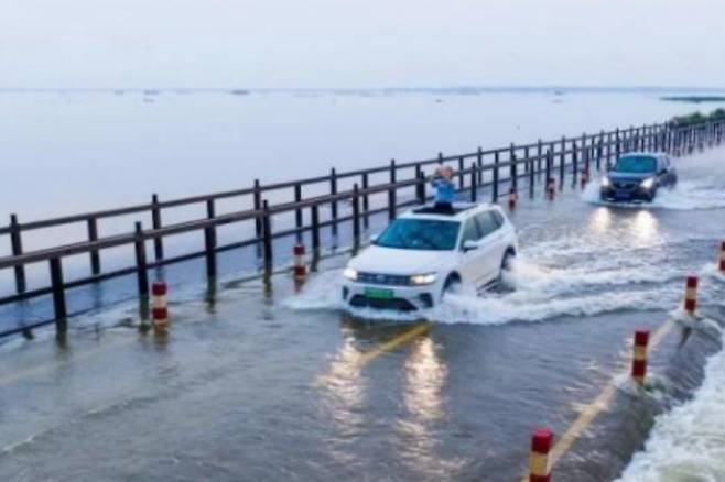 물이 넘친 장시성 지우장시의 호수주변 도로에서 차량들이 아슬아슬하게 지나가고 있다. 바이두 홈페이지 캡처