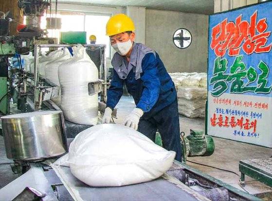 북한 노동당 기관지 노동신문에 실린 사진. '당 결정을 목숨으로' 등 선전문구가 걸린 평안북도 안주시 소재 남흥청년화학연합기업소 내부. 컨베이어벨트 등 작업장 주변에 아무런 안전장치가 없다. 뉴스1