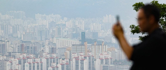 한 시민이 서울 남산에서 도심 시내 아파트 단지를 사진 촬영하고 있다. <연합뉴스>