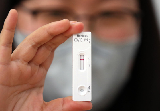 A staff from Humasis holds up an antigen Covid-19 test kit durings instruction to teach call center workers in Seongdong District, eastern Seoul, on how to use the kit on May 17. [YONHAP]