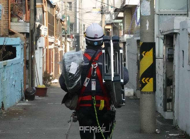 ▲케이블·인터넷 설치 노동자가 사다리와 UTP선 등 작업에 필요한 장비를 들고 가입자의 집으로 향하고 있다. 사진=금준경 기자