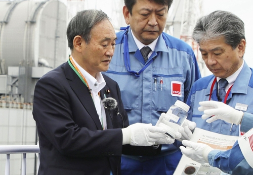 스가 요시히데 일본 총리가 지난해 9월 일본 후쿠시마 제1원전에서 정화처리한 방사성 물질 오염수가 든 용기를 들고 있다. /교도연합뉴스