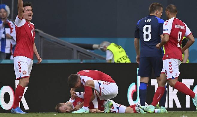 덴마크 축구대표팀 크리스티안 에릭센이 13일 덴마크 코펜하겐의 파르켄 스타디움에서 열린 유로 2020 핀란드의 조별리그 B조 1차전 도중 의식을 잃고 쓰러지자 팀 동료들이 달려와 살펴보고 있다. 코펜하겐=AP연합뉴스