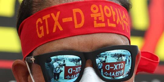 지난 2일 정부세종청사 국토교통부 앞에서 열린 'GTX-D 원안사수!' 경기 김포∼하남 노선 반영과 서울 5호선 김포 연장을 촉구하는 집회에서 한 참석자의 선글라스에 손피켓이 비치고 있다. <연합뉴스>