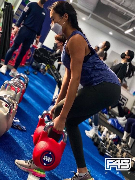 양손에 12kg의 덤벨을 들고 하는 운동 동작. 하체 근력을 강화해주는 운동법이다.