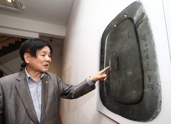 이근배 시인이 15일 서울 가나아트센터에서 열린 소장품전에서 ‘정조대왕사은연’을 확대한 사진을 가리키며 벼루에 대해 설명하고 있다. 연합뉴스