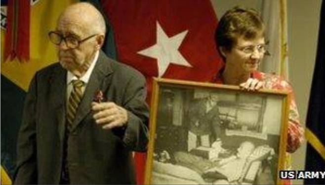 존 윌퍼스가 도조 히데키의 권총 자살 시도를 막는 사진을 들고 딸과 함께 포즈를 취하고 있다.BBC 자료사진